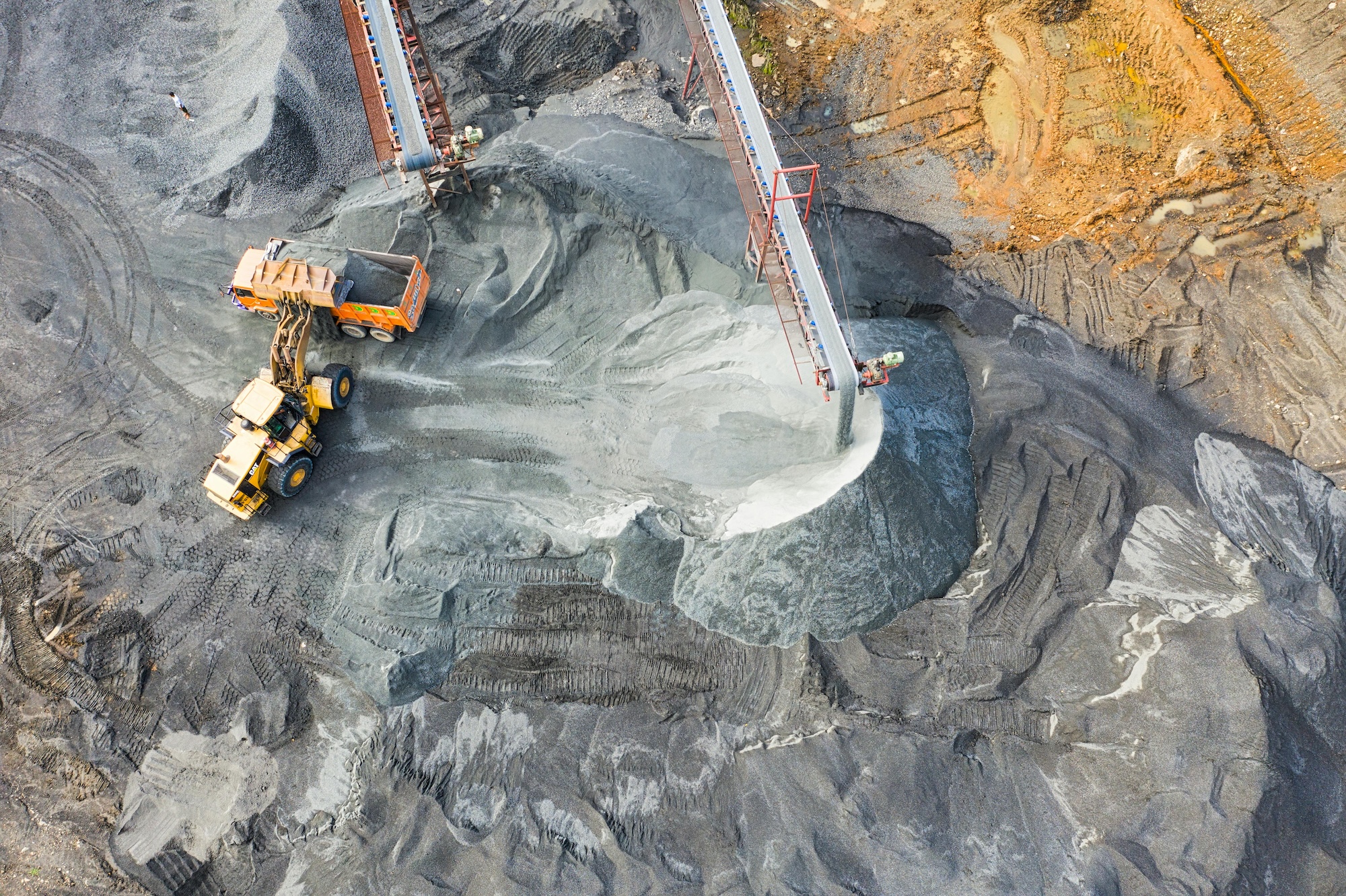 Aerial view of aggregate mining site with conveyor belts loading material into a dump truck