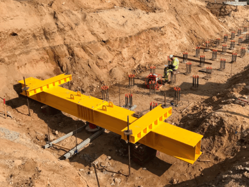 PileSense static load test setup at construction site with yellow reaction beam and test piles